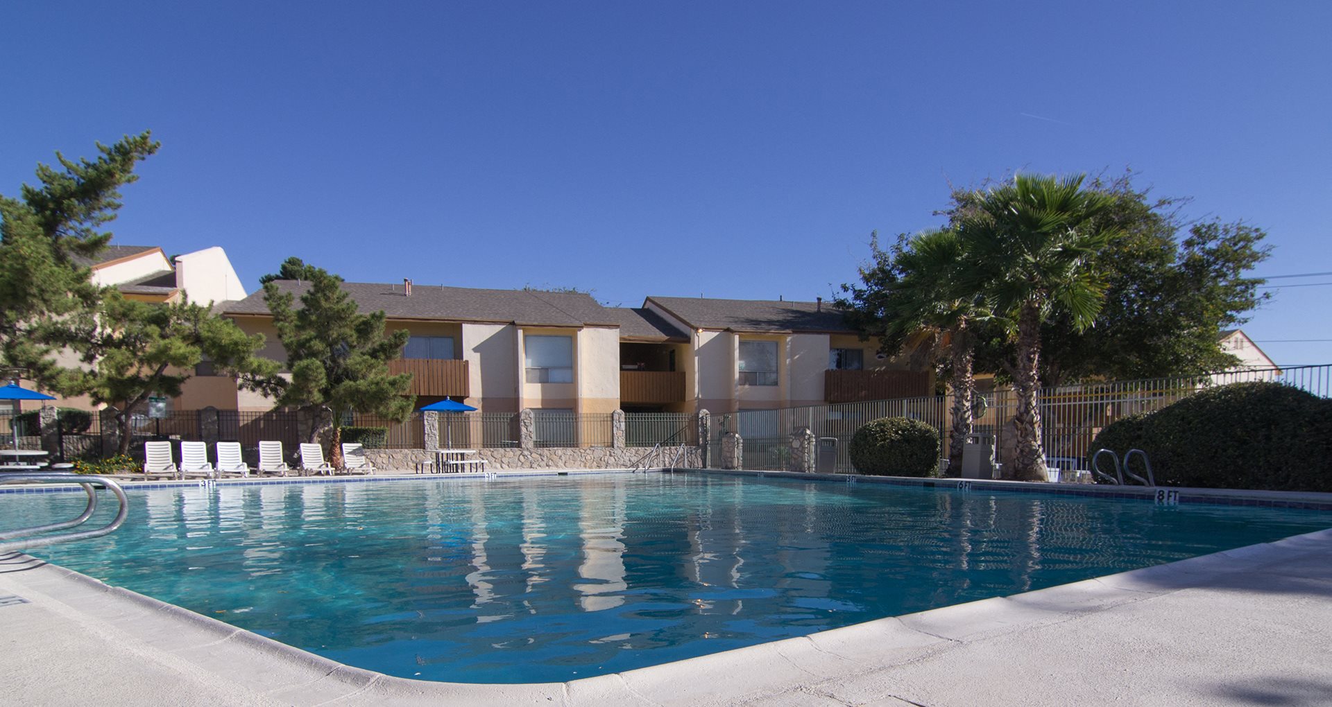 Pool, lounge chairs, apt building  Ridgemar Apts For Rent l El Paso TX